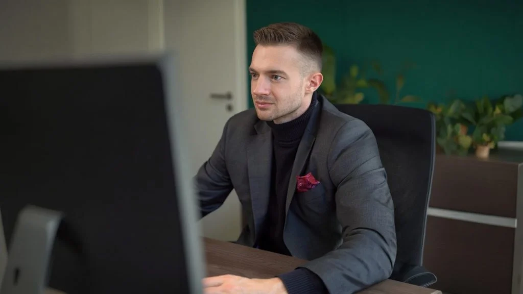 Konzentrierter Steuerberater Patrick Herzer arbeitet fokussiert an seinem Computerbildschirm in der Kanzlei